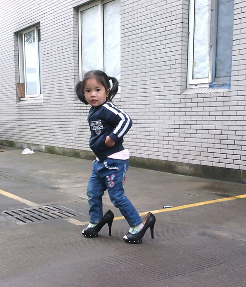 爱美的小女孩，穿着妈妈的高跟鞋。