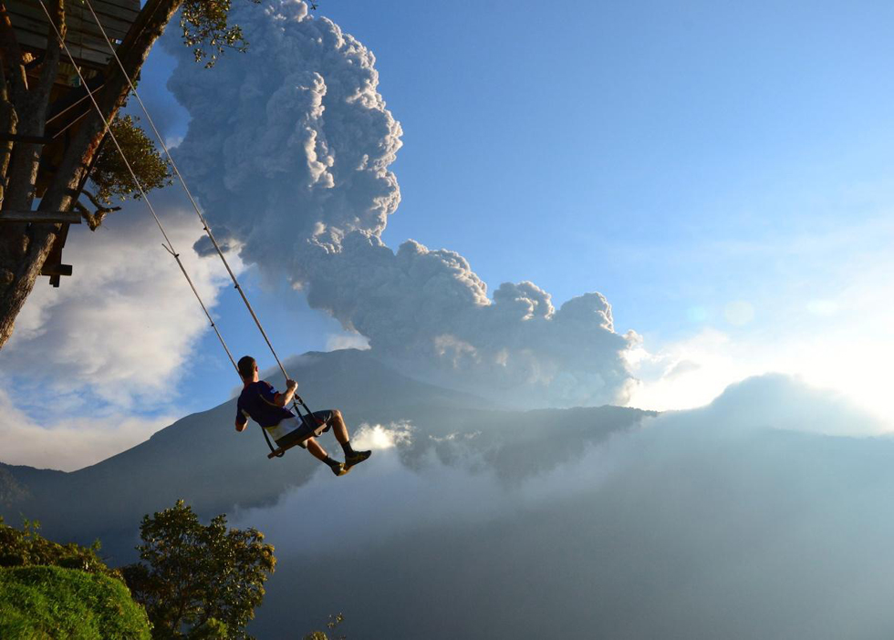 在厄瓜多尔巴诺斯（Banos）“世界尽头”拍摄的这张照片中，一名男子摇荡在秋千上，俯瞰正在喷发的通古拉瓦(Tungurahua)火山。