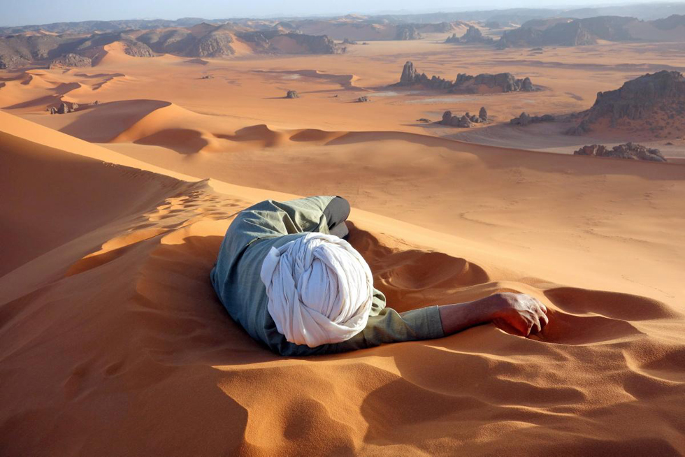 一名游客在撒哈拉沙漠最大的沙丘上休息，摄影：Evan Cole