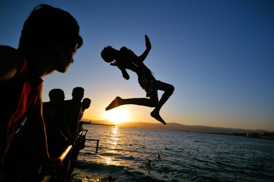 在约旦亚喀巴，一个小伙子从码头上跳进了红海中。摄影师：乌尔里奇-兰姆伯特。