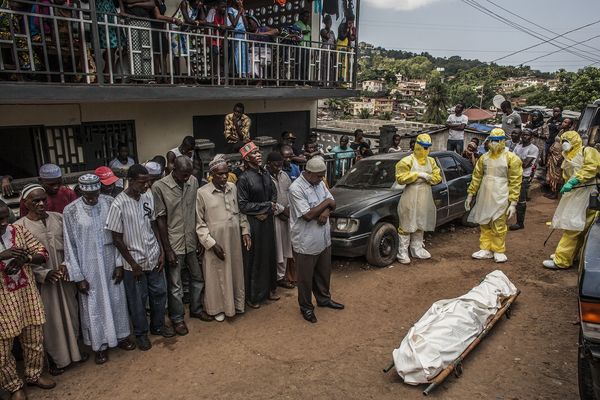 安全埋葬小组将一名可能感染伊波拉的27岁男子的尸体从家中搬离后，朋友和家人为他祈祷。埋葬小组经常会中断他们的工作，让亲属有机会透过简短的仪式对死者致意。 （Ph