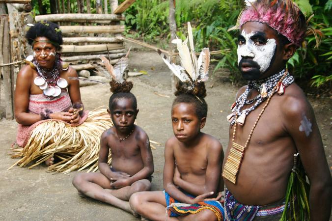 在这张摄于2007年的照片中，巴布亚新几内亚的一名酋长与妻小坐在一起。按照当地习俗，男性以猪为货币购买妻子。 PHOTOGRAPH BY ALBERT PODE