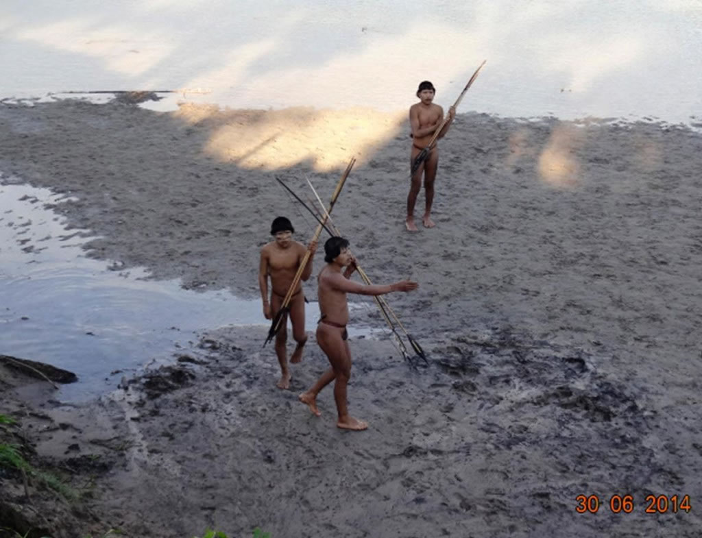 在辛帕蒂亚村的恩维拉河河畔，过去与世隔绝、名为查帕纳瓦的部落成员，正朝巴西政府官员走去。 Photograph by Funai, Reuters