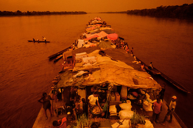 夕阳洒在超载的驳船上，驳船的引擎突突作响，向刚果河上游前进。 Photograph by Pascal Maitre