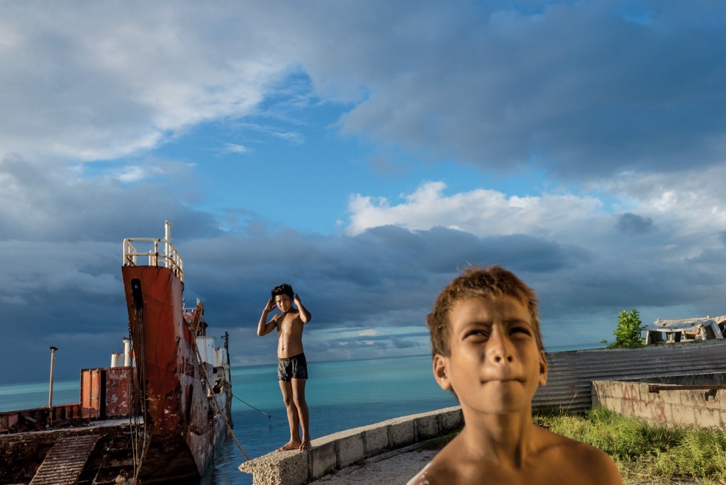 塔拉瓦环礁海堤上的男孩看着一场风暴接近。逐渐暖化的大气预计将为吉里巴斯以及中太平洋的其他岛国带来更多降雨。 Photograph by Kadir van Lo