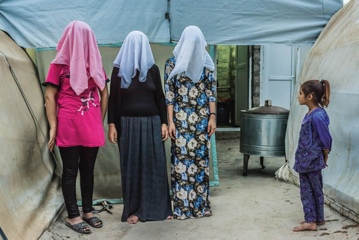 小女孩看着一名母亲（中）和她的女儿（左）及媳妇同时掩着脸入镜。这些女性都是库尔德族群内为数更少的亚兹迪人。图中的女儿和她的小姑说，她们被迫嫁给伊斯兰国战士，后来