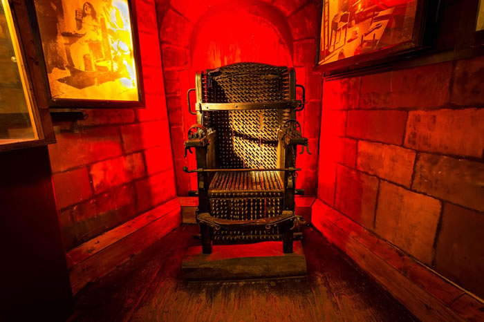 酷刑博物馆中恐怖的宗教法庭座椅陈列室，展示了放大的古籍图片，并有文章说明这种座椅的历史和使用方式。 PHOTOGRAPH BY MICHIEL VAARTJES