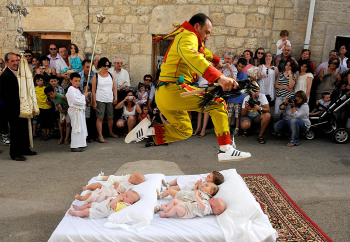 在穆西亚城堡的跳婴儿节中，象征魔鬼的男子从婴儿身上跳过去。 PHOTOGRAPH BY DENIS DOYLE, GETTY IMAGES