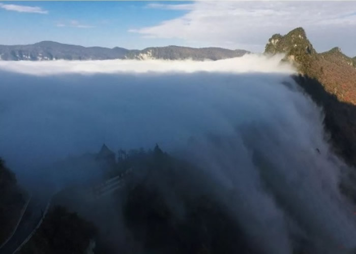 云雾自山体一侧向山谷“俯冲”而下，如天河倾泻，气势磅礴。