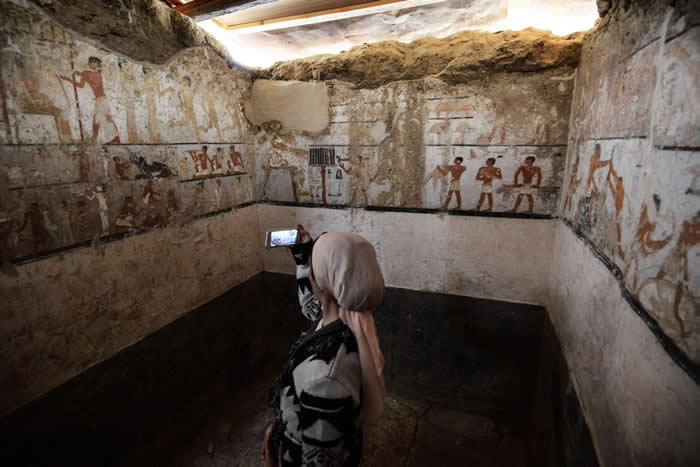 女子在古墓中拍照，墓室座落在开罗的吉萨平原上，属于古王国（Old Kingdom）时期一名女祭司，墓中装饰着保存良好的珍稀壁画。 PHOTOGRAPH BY M