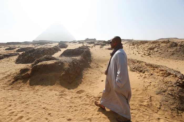 男子走在开罗郊区吉萨平原新发现的古墓附近，这里有三座古代金字塔。 PHOTOGRAPH BY AMR ABDALLAH DALSH, REUTERS