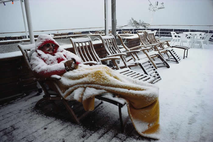 阿曼森海（Amundsen Sea）附近，有一位认真的南极游客，在下雪时还睡在甲板椅上。 PHOTOGRAPH BY COLIN MONTEATH, MINDE