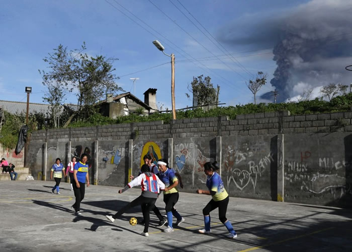 火山喷灰烬的同时，附近城镇有女子踢足球。