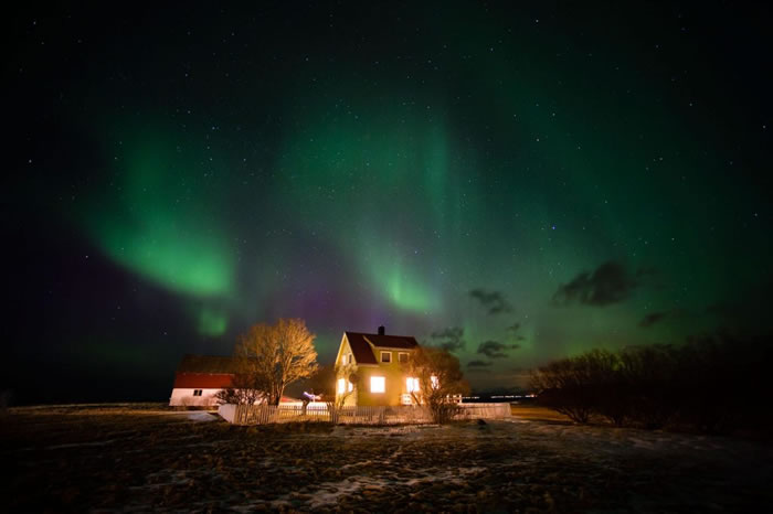 北极光照亮挪威房舍上的天空。 PHOTOGRAPH BY SERGIO PITAMITZ, NATIONAL GEOGRAPHIC CREATIVE