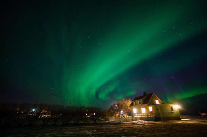 挪威诺尔兰郡（Nordland）的这座房子，沐浴在流淌而过的极光之中。 PHOTOGRAPH BY SERGIO PITAMITZ, NATIONAL GEOG