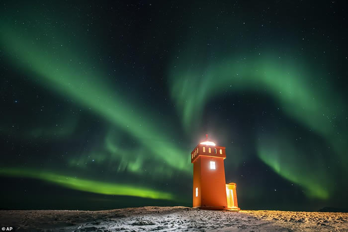 冰岛Grundarfjorour村灯塔上方天空中的北极光。极光是由来自太阳的高能带电粒子与地球大气层中的气体分子之间的相互作用引起的。
