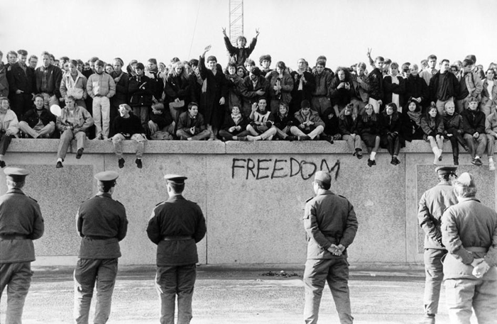 在柏林围墙倒下的1989年11月，西德民众在东德卫兵面前爬上了这道冷战藩篱。 PHOTOGRAPH BY HESSE, ULLSTEIN BILD/GETTY