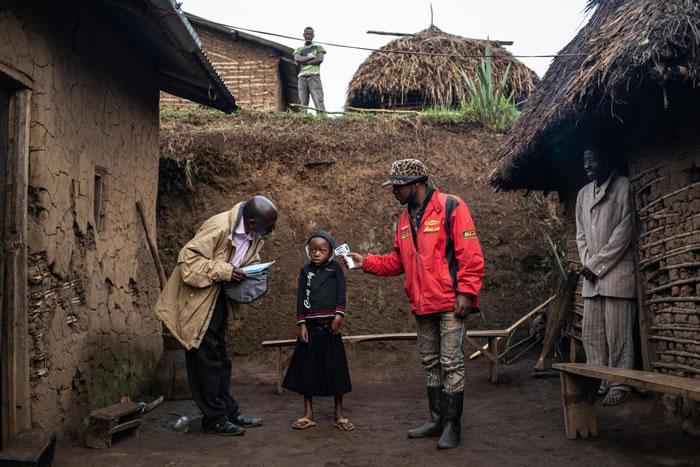 2019年，一个WHO团队在瓦亚纳镇为7岁的康福美. 马斯卡. 穆格汉伊拉（Confirme Masika Mughanyira）检查体温，该镇位于DRC布滕博