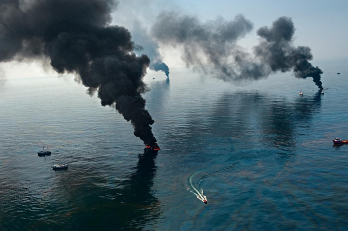2010年4月深水地平线漏油事件后的墨西哥湾，烟雾从被清除人员点燃的表面油污中升起。 PHOTOGRAPH BY JOEL SARTORE， NAT GEO I
