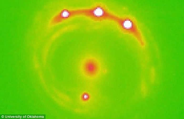 图为首次发现银河系外行星的RX J1131-1231星系的引力透镜图像。中间的红色圆点是前景星系，这个星系中估计包含有万亿以上的行星。白点圆点代表了遥远背景天体
