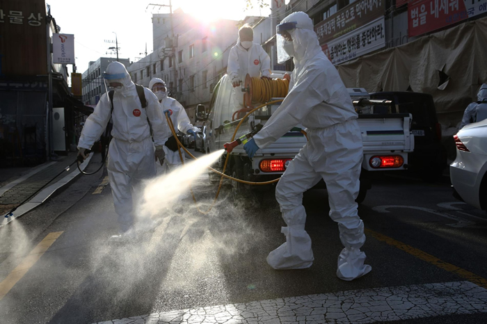 2020年10月6日韩国首尔，穿戴个人防护装备的消毒工人在清理一条街，以预防冠状病毒传播。韩国的新型冠状病毒病例已经连续第六天维持在100例以下，但该国正在为秋