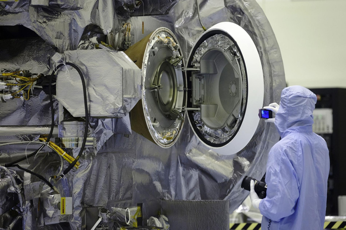 肯尼迪太空中心（Kennedy Space Center）的技术人员在2016年测试舱门时，将门打开检查样品返回舱（影像右侧圆形物体）的内部。泄漏样本的采样头被