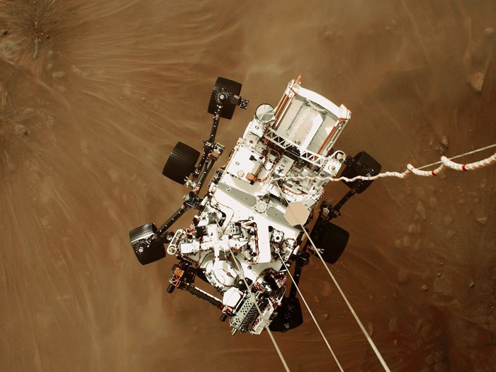 利用「空中吊车」协助探测车着陆──机载相机拍摄了毅力号探测车成功登陆火星的影像和影片，此时的探测车以电缆与空中吊车相连，再数公尺就要轻触火星地表。 PHOTO