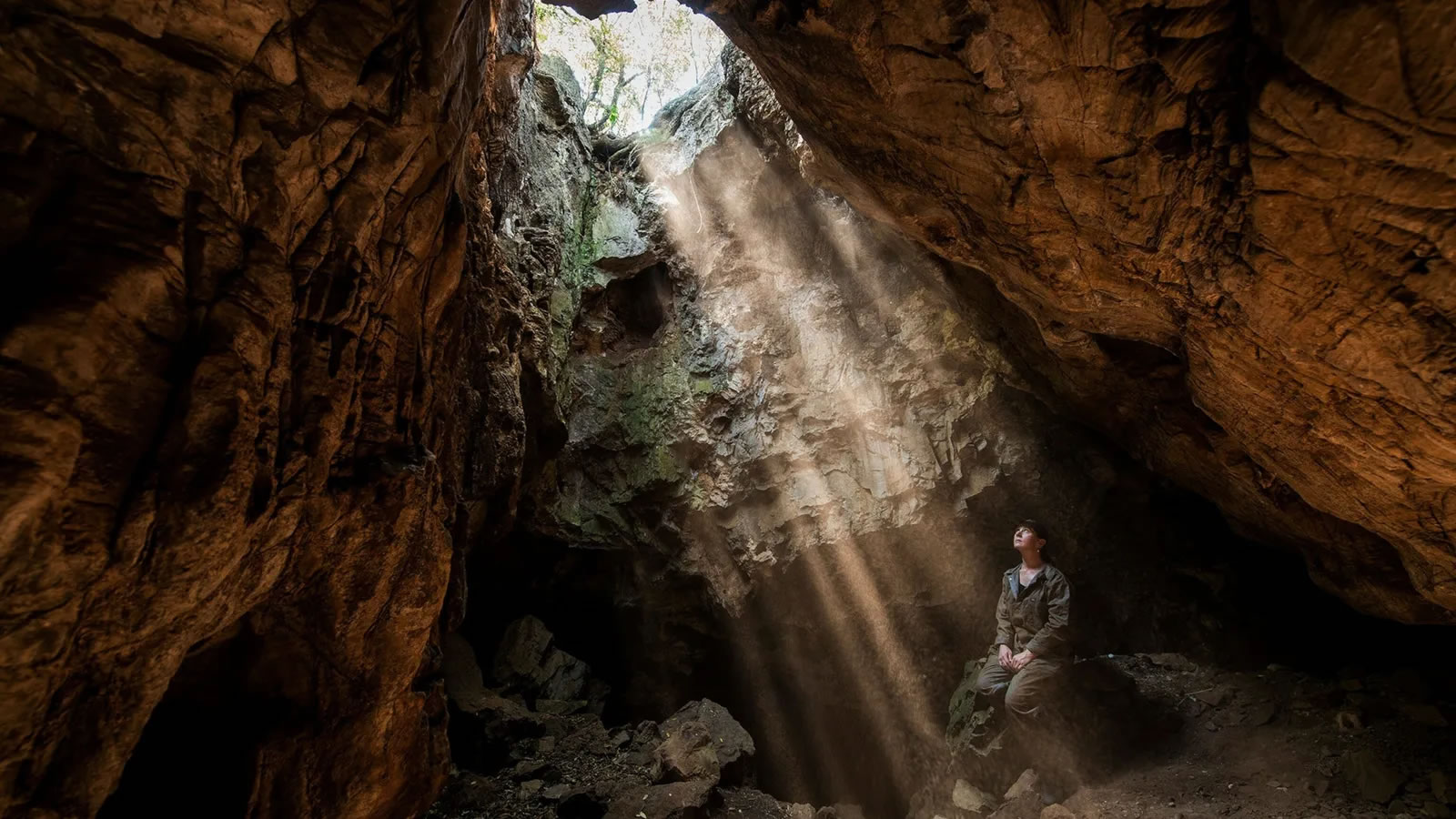 人类学家Marina Elliott坐在南非升星岩洞系统的入口处。她的团队在洞穴蜿蜒的隧道网络深处发现了这些新出土的遗骸。摄影：ROBERT CLARK